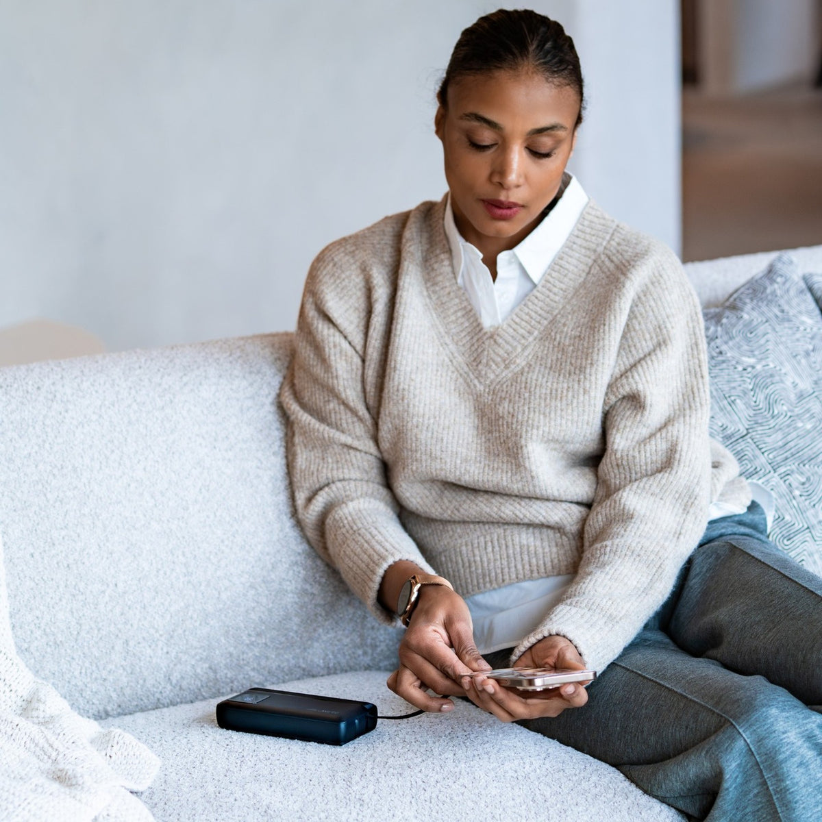 Vrouw op de bank laadt haar telefoon op met de Siltcon powerbank